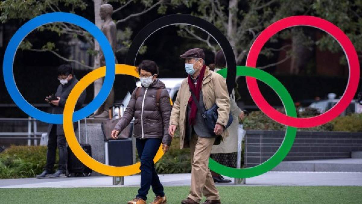 People wearing protective face masks, following an outbreak of the coronavirus, are seen next to the Olympic rings in front of the Japan Olympic Museum in Tokyo, Japan, February 26, 2020. REUTERS/Athit Perawongmetha
