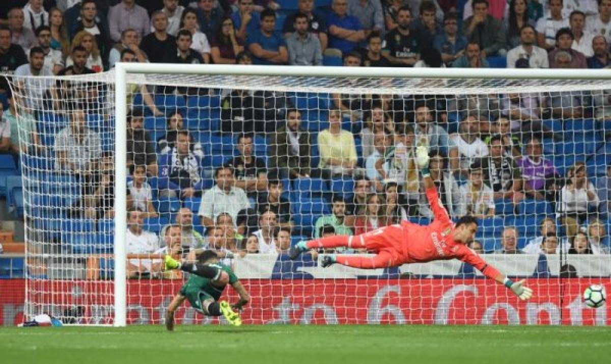 Real Betis' forward from Paraguay Arnaldo Sanabria (L) heads the ball to score a goal as Real Madrid's goalkeeper from Costa Rica Keylor Navas dives for the ball during the Spanish league football match Real Madrid CF against Real Betis at the Santiago Bernabeu stadium in Madrid on September 20, 2017. / AFP PHOTO / GABRIEL BOUYS
