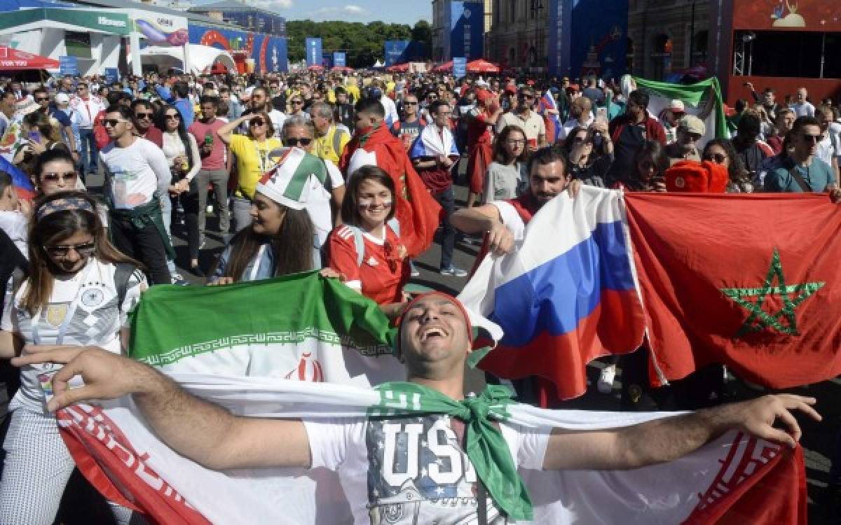 Iran's fans and Russia's fans arrive to follow the game between Russia and Saudi Arabia on a giant screen at the Fifa Fans Fest Saint Petersburg on June 14, 2018 during the Russia 2018 football World Cup tournament. / AFP PHOTO / OLGA MALTSEVA