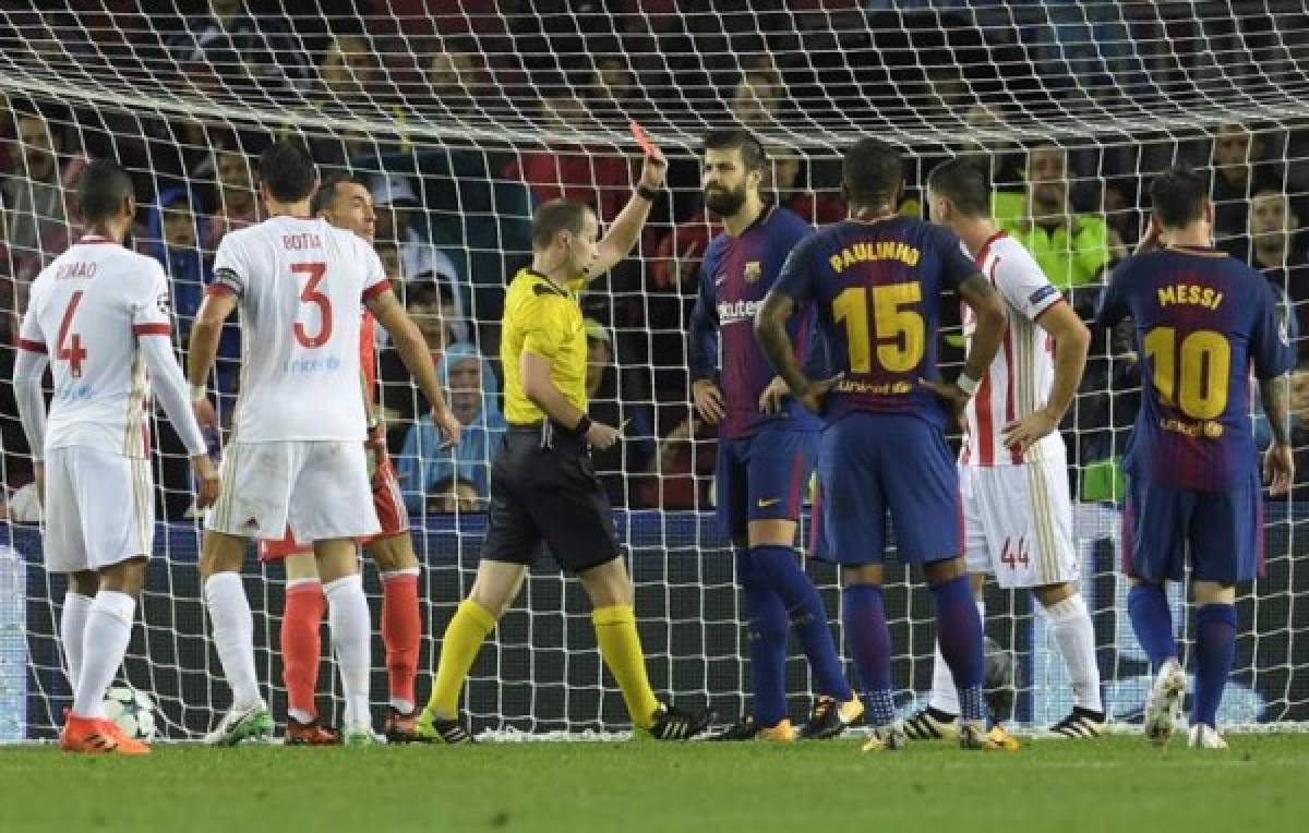 Barcelona's Spanish defender Gerard Pique (C) receives a second yellow card during the UEFA Champions League group D football match FC Barcelona vs Olympiacos FC at the Camp Nou stadium in Barcelona on Ocotber 18, 2017. / AFP PHOTO / LLUIS GENE
