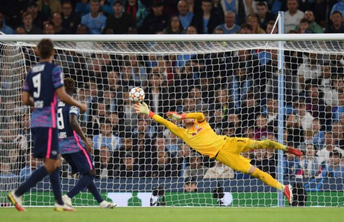 RB Leipzig's Hungarian goalkeeper Peter Gulacsi dives in vain to save a shot from Manchester City's Portuguese defender Joao Cancelo (not seen) for their fifth goal during the UEFA Champions League 1st round Group A football match between Manchester City and RB Leipzig at the Etihad Stadium in Manchester, north west England, on September 15, 2021. (Photo by Oli SCARFF / AFP)