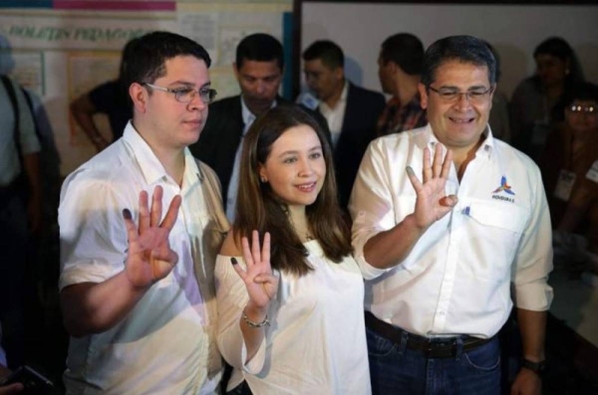 This handout picture released by Honduras' Presidency shows Honduran President Juan Orlando Hernandez (R), posing for a picture next to his son Juan Orlando (L) and his daughter Daniela as they show 4 fingers (for re-election term) after casting his ballot at a polling station in Gracias, Lempira department, 180 km from Tegucigalpa, during the general election on November 26, 2017. Honduras' six million voters are to cast ballots in a controversial election Sunday in which President Juan Orlando Hernandez is seeking a second mandate despite a constitutional one-term limit. This small country is at the heart of Central America's 'triangle of death,' an area plagued by gangs and poverty. / AFP PHOTO / Honduras' Presidency / HO / RESTRICTED TO EDITORIAL USE - MANDATORY CREDIT 'AFP PHOTO / Honduras' Presidency' - NO MARKETING NO ADVERTISING CAMPAIGNS - DISTRIBUTED AS A SERVICE TO CLIENTS