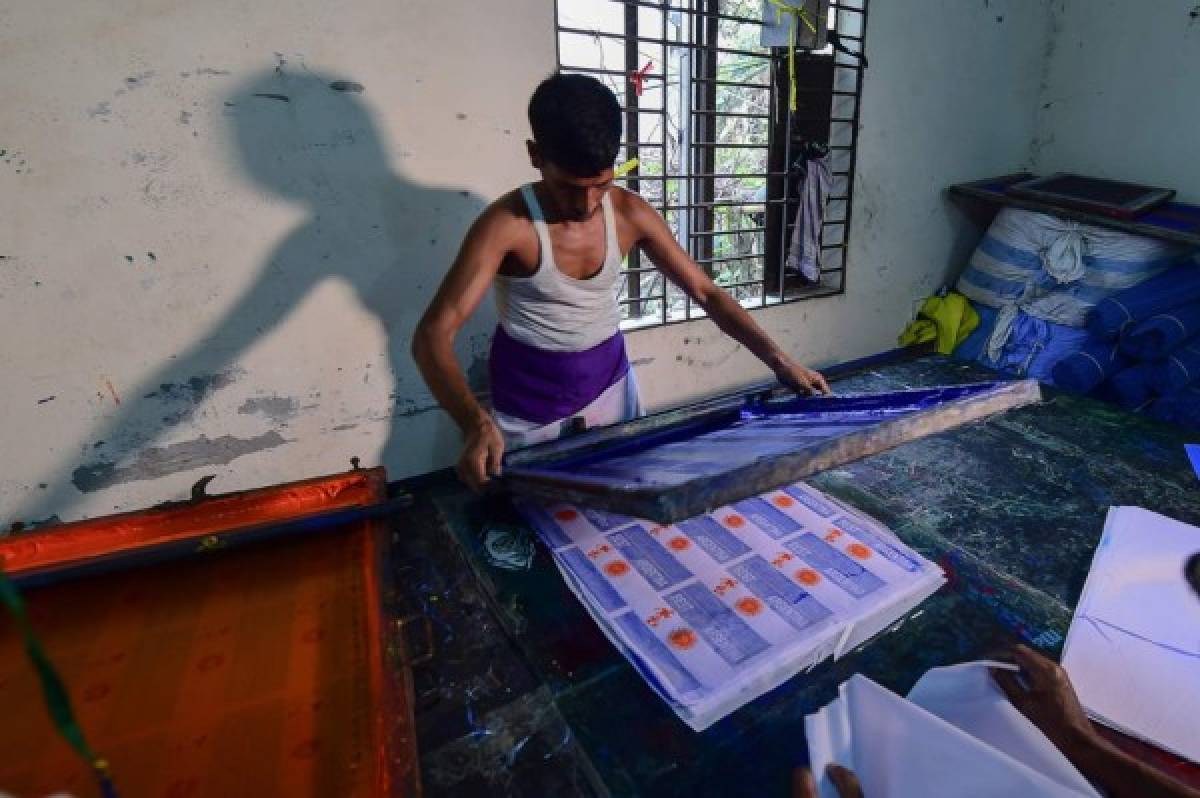 This photograph taken on May 17, 2018, shows a Bangladeshi worker using a silk-screen for printing Argentina flags in Narayanganj, on the outskirts of Dhaka, ahead of the 2018 football World Cup. Flag makers in Bangladesh are doing a roaring trade weeks ahead of the World Cup, but no-one is interested in the home nation's colours -- the money is all on pennants for Lionel Messi's Argentina and Neymar's Brazil. / AFP PHOTO / Munir UZ ZAMAN / TO GO WITH AFP STORY FBL-WC-2018-BAN-BANGLADESH-FLAGS,FOCUS BY SHAFIQUL ALAM