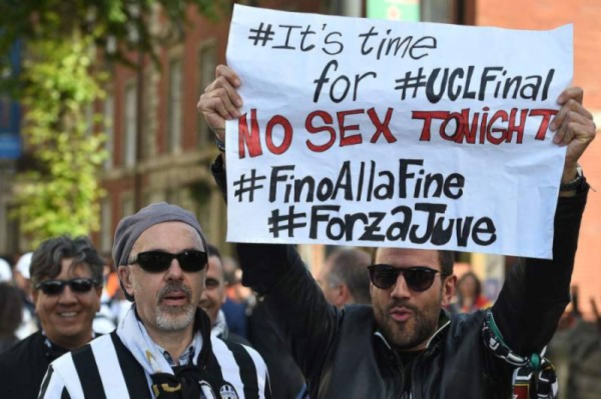 A Juventus supporter holds up a sign as he makes his way to the stadium ahead of the UEFA Champions League final football match between Juventus and Real Madrid in Cardiff, south Wales, on June 3, 2017. / AFP PHOTO / Oli SCARFF