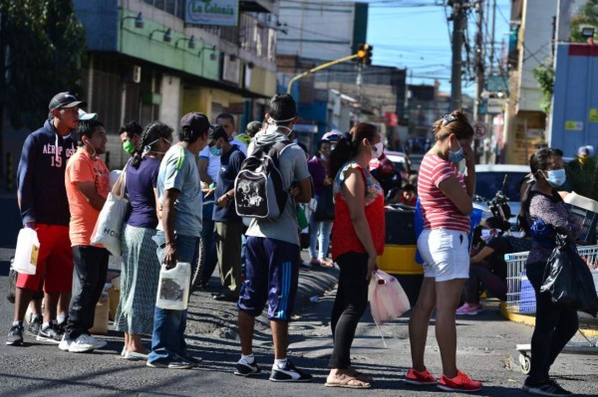 People stand in a queue to buy kerosene oil at a fuel station in Tegucigalpa on March 27, 2020. - The National System of Risks (SINAGER) confirmed the first dead and 16 new cases of COVIN-19, rising to 68 the confirm cases in Honduras. (Photo by ORLANDO SIERRA / AFP)