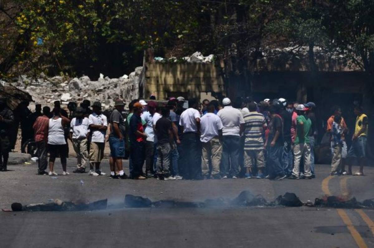 Drivers and workers related to the public transport block a street in Tegucigalpa, on March 24, 2020 to protest against 'an absolute curfew' decreed by the government to force the population to isolate themselves in their homes and curb the spread of the COVID-19 coronavirus. (Photo by ORLANDO SIERRA / AFP)