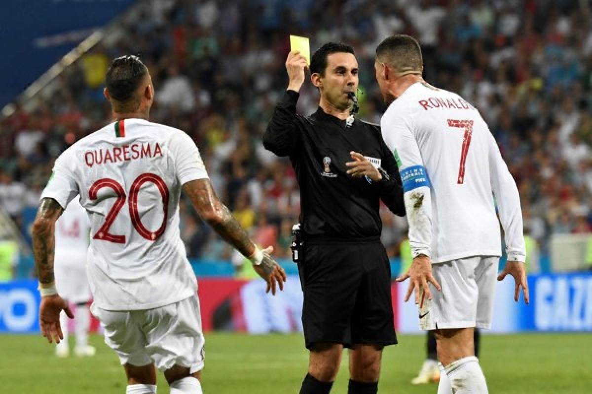 Mexican referee Cesar Ramos (C) shows a yellow card to Portugal's forward Cristiano Ronaldo during the Russia 2018 World Cup round of 16 football match between Uruguay and Portugal at the Fisht Stadium in Sochi on June 30, 2018. / AFP PHOTO / Jonathan NACKSTRAND / RESTRICTED TO EDITORIAL USE - NO MOBILE PUSH ALERTS/DOWNLOADS