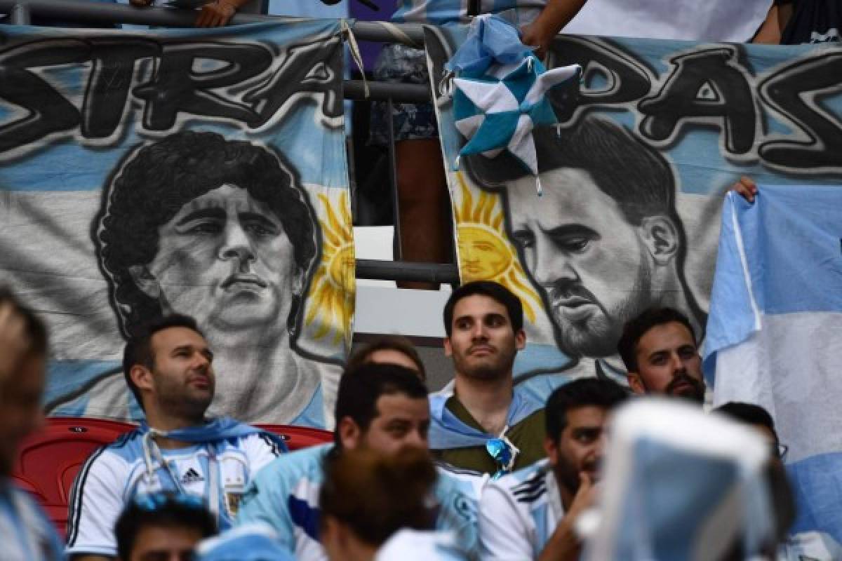 Argentina fans sit in front of banners with the images of Argentina's forward Lionel Messi (R) and former Argentina football player Diego Maradona before the Russia 2018 World Cup round of 16 football match between France and Argentina at the Kazan Arena in Kazan on June 30, 2018. / AFP PHOTO / Jewel SAMAD / RESTRICTED TO EDITORIAL USE - NO MOBILE PUSH ALERTS/DOWNLOADS