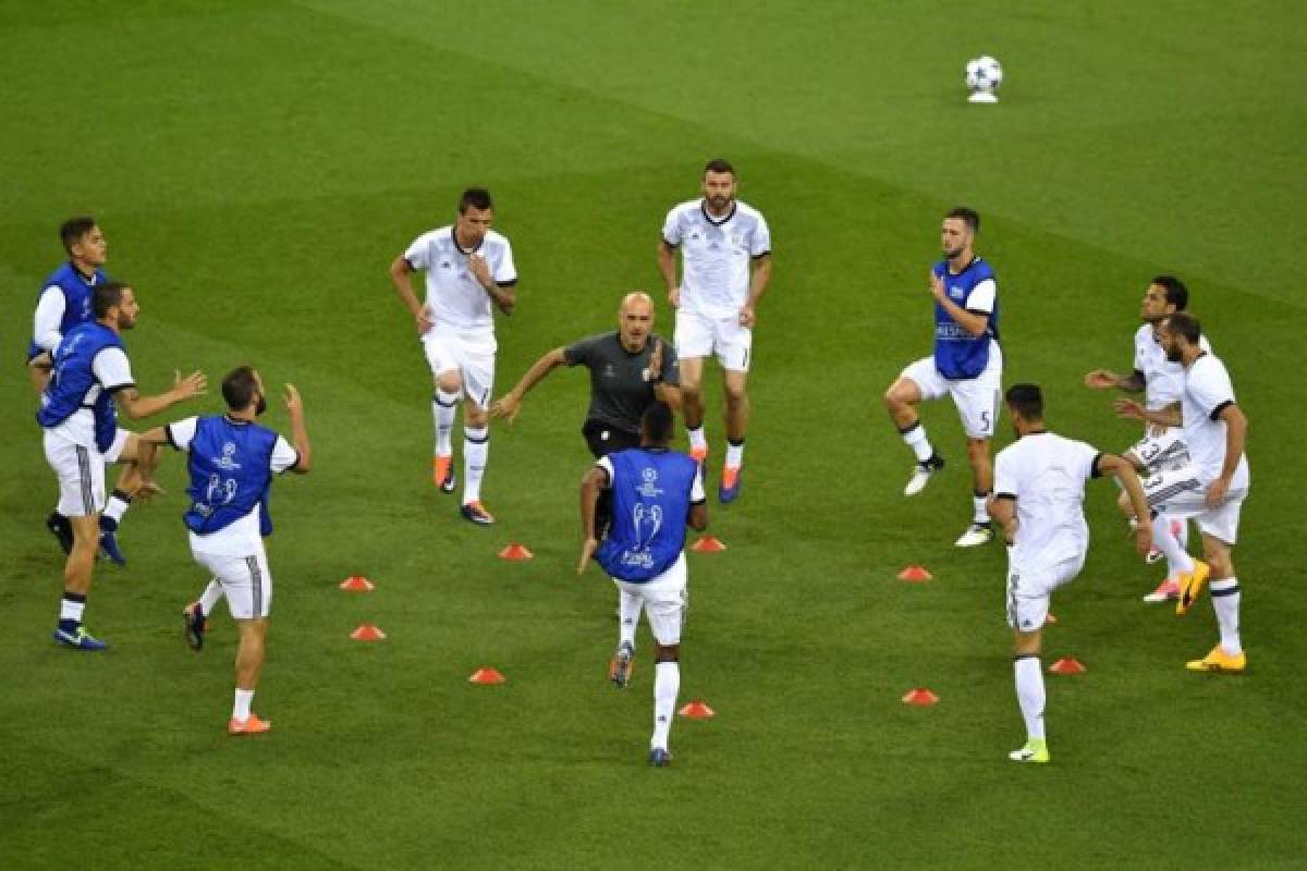 Juventus' athletic performance head coach Simone Folletti (C) leads the warm up under the look of Juventus' Croatian striker Mario Mandzukic, Juventus' Italian defender Andrea Barzagli and Juventus' Bosnian midfielder Miralem Pjanic (bottom) prior to the UEFA Champions League final football match between Juventus and Real Madrid at The Principality Stadium in Cardiff, south Wales, on June 3, 2017. / AFP PHOTO / Ben STANSALL