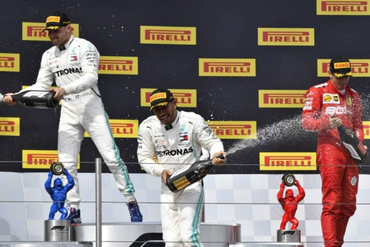 Winner Mercedes' British driver Lewis Hamilton (C) celebrates with champagne on the podium with second placed Mercedes' Finnish driver Valtteri Bottas (L) and third placed Ferrari's Monegasque driver Charles Leclerc (R) after the Formula One Grand Prix de France at the Circuit Paul Ricard in Le Castellet, southern France, on June 23, 2019. (Photo by GERARD JULIEN / AFP)