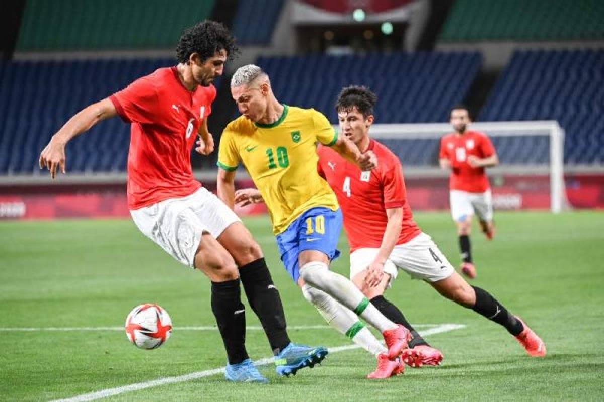 Brazil's forward Richarlison is marked by Egypt's defender Ahmed Hegazi (L) and Egypt's defender Osama Galal (R) during the Tokyo 2020 Olympic Games men's quarter-final football match between Brazil and Egypt at Saitama Stadium in Saitama on July 31, 2021. (Photo by Charly TRIBALLEAU / AFP)