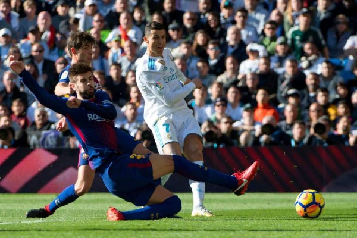 Barcelona's Spanish defender Gerard Pique (L) vies with Real Madrid's Portuguese forward Cristiano Ronaldo during the Spanish League 'Clasico' football match Real Madrid CF vs FC Barcelona at the Santiago Bernabeu stadium in Madrid on December 23, 2017. / AFP PHOTO / CURTO DE LA TORRE