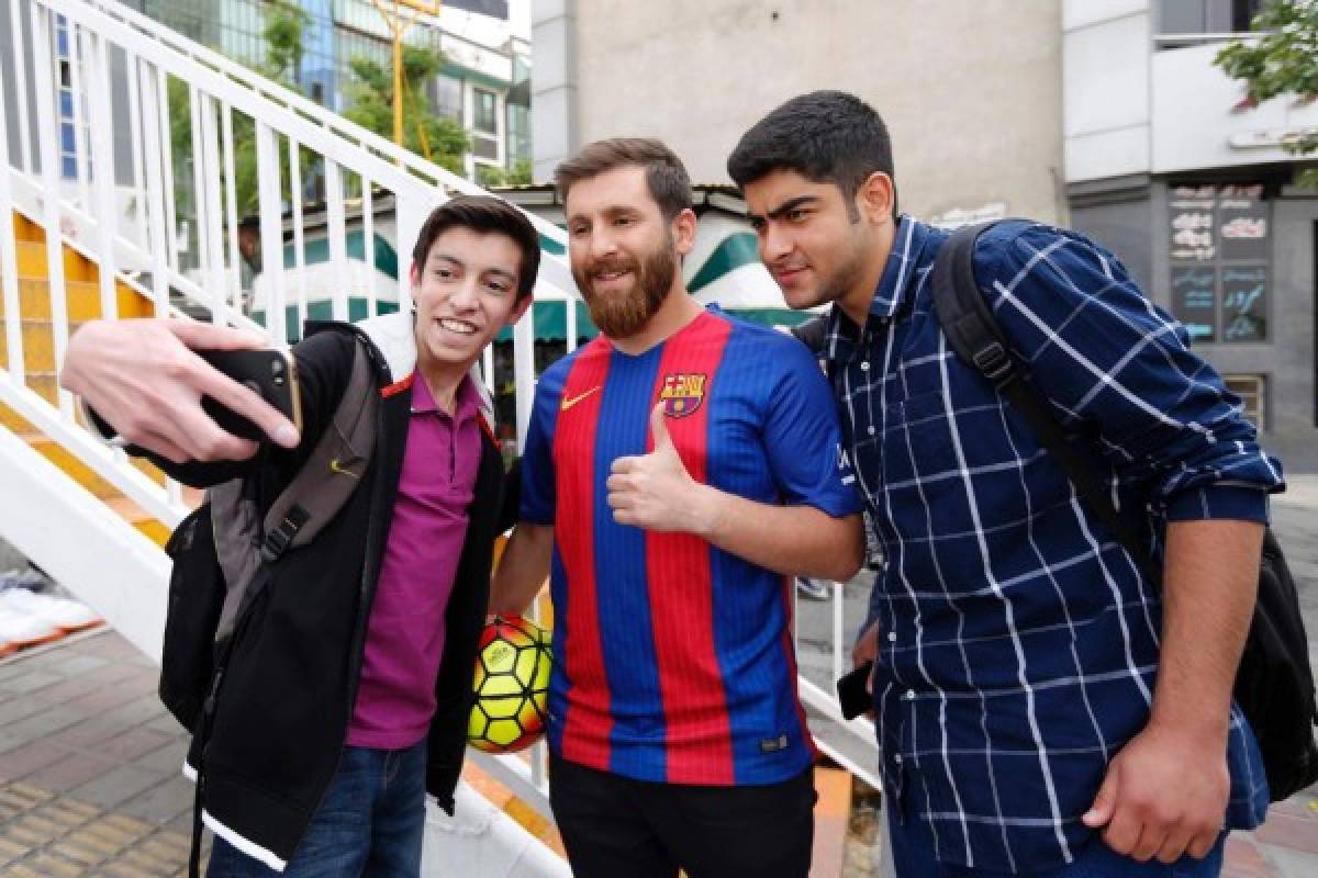 Reza Parastesh, a doppelganger of Barcelona and Argentina's footballer Lionel Messi, poses for a picture with fans in a street in Tehran on May 8, 2017. / AFP PHOTO / ATTA KENARE