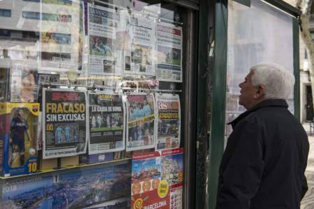 A man watches the front pages of sports newspapers on display in a kiosk in Barcelona on April 11, 2018 a day after the victory of AS Roma over FC Barcelona in the UEFA Champions League round of quarter-final second leg football match.Barcelona's shock Champions League exit at the hands of Roma does not discount what is likely to be a double-winning season but the loss should serve as a warning for what comes next. After the 3-0 defeat at Stadio Olimpico, which sent Roma through on away goals, Ernesto Valverde paid lip-service to shouldering responsibility but in the same breath pointed to a disappointment with his players. / AFP PHOTO / Josep LAGO