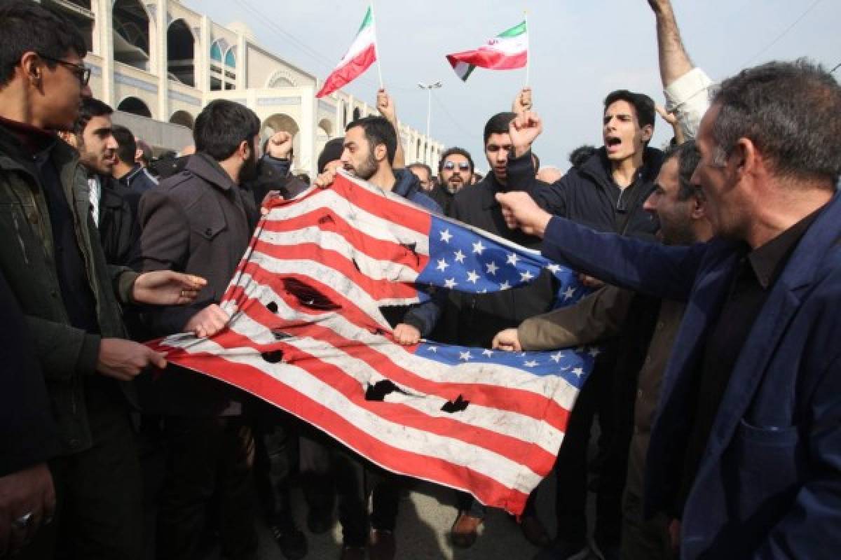 Iranians tear up a US flag during a demonstration in Tehran on January 3, 2020 following the killing of Iranian Revolutionary Guards Major General Qasem Soleimani in a US strike on his convoy at Baghdad international airport. - Iran warned of 'severe revenge' and said arch-enemy the United States bore responsiblity for the consequences after killing one of its top commanders, Qasem Soleimani, in a strike outside Baghdad airport. (Photo by ATTA KENARE / AFP)