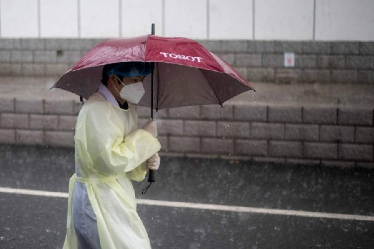 A medical worker wearing protective gear as a preventive measure against the COVID-19 coronavirus checks uses an umbrella outside Huanggang Zhongxin Hospital in Huanggang, in China’s central Hubei province on March 26, 2020. (Photo by NOEL CELIS / AFP)
