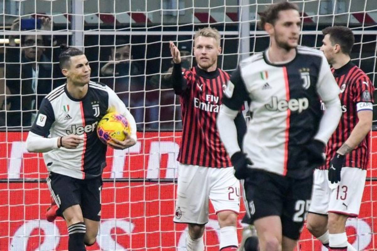 Juventus' Portuguese forward Cristiano Ronaldo (L) grabs the ball as he celebrates after scoring a penalty as AC Milan's Danish defender Simon Kjaer (C) reacts during the Italian Cup (Coppa Italia) semi-final first leg football match AC Milan vs Juventus Turin on February 13, 2020 at the San Siro stadium in Milan. (Photo by Alberto PIZZOLI / AFP)