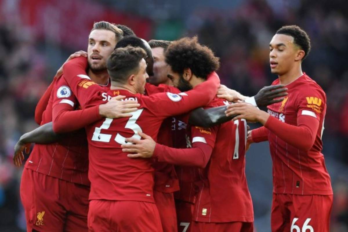 Liverpool's Egyptian midfielder Mohamed Salah celebrates with teammates after scoring his team's first goal during the English Premier League football match between Liverpool and Watford at Anfield in Liverpool, north west England on December 14, 2019. (Photo by Paul ELLIS / AFP) / RESTRICTED TO EDITORIAL USE. No use with unauthorized audio, video, data, fixture lists, club/league logos or 'live' services. Online in-match use limited to 120 images. An additional 40 images may be used in extra time. No video emulation. Social media in-match use limited to 120 images. An additional 40 images may be used in extra time. No use in betting publications, games or single club/league/player publications. /