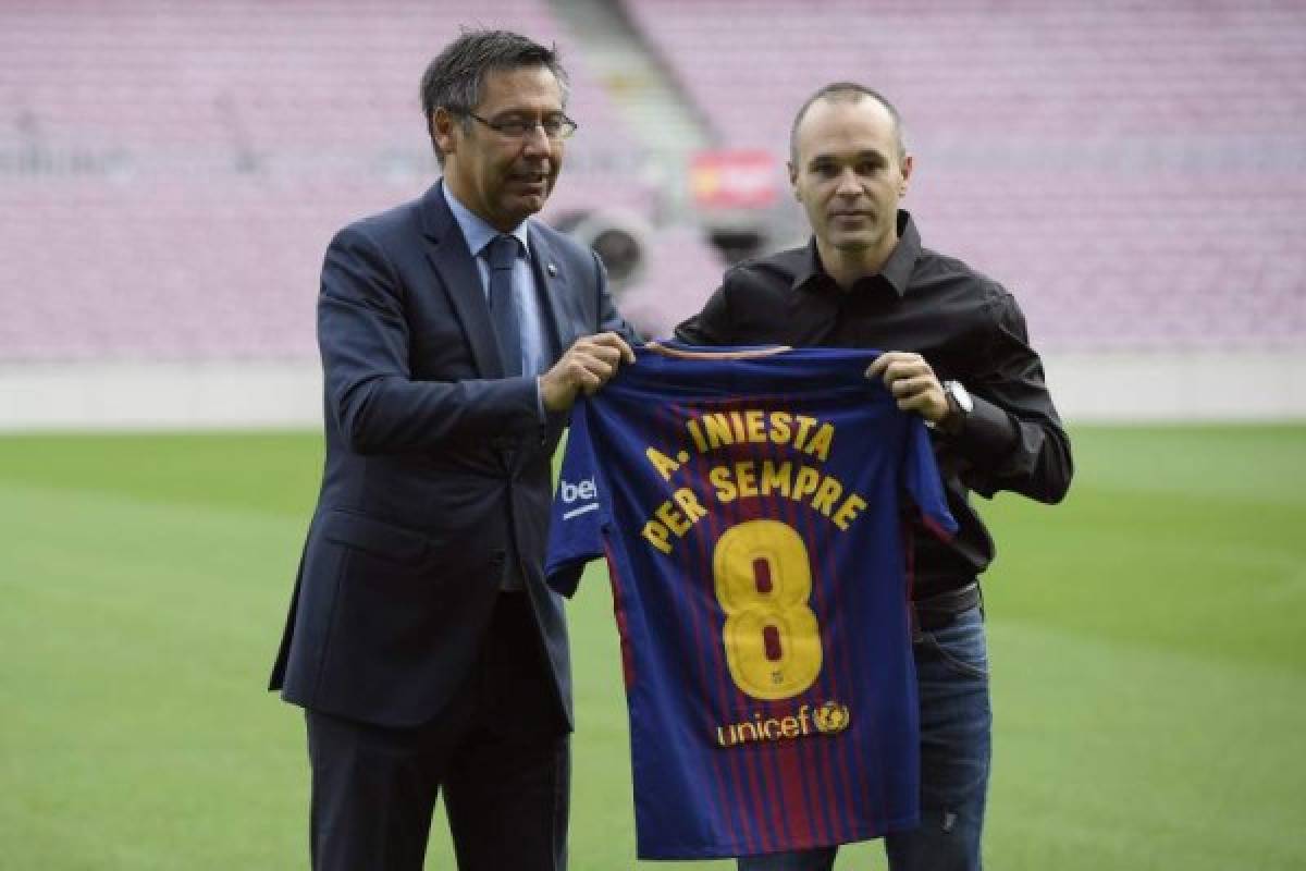 Barcelona's midfielder Andres Iniesta poses with a special Barcelona FC jersey next to the Catalan club's president Josep Maria Bartomeu (L) after renewing his contract at the Camp Nou in Barcelona on October 6, 2017.Barcelona tied down captain Andres Iniesta for the rest of his career as the club announced the 33-year-old midfielder has agreed a 'lifetime contract'. Normally determined to shy away from the spotlight, Iniesta spoke out to urge negotiation and prevent a spiralling political crisis over the battle for Catalan independence deepening. / AFP PHOTO / LLUIS GENE