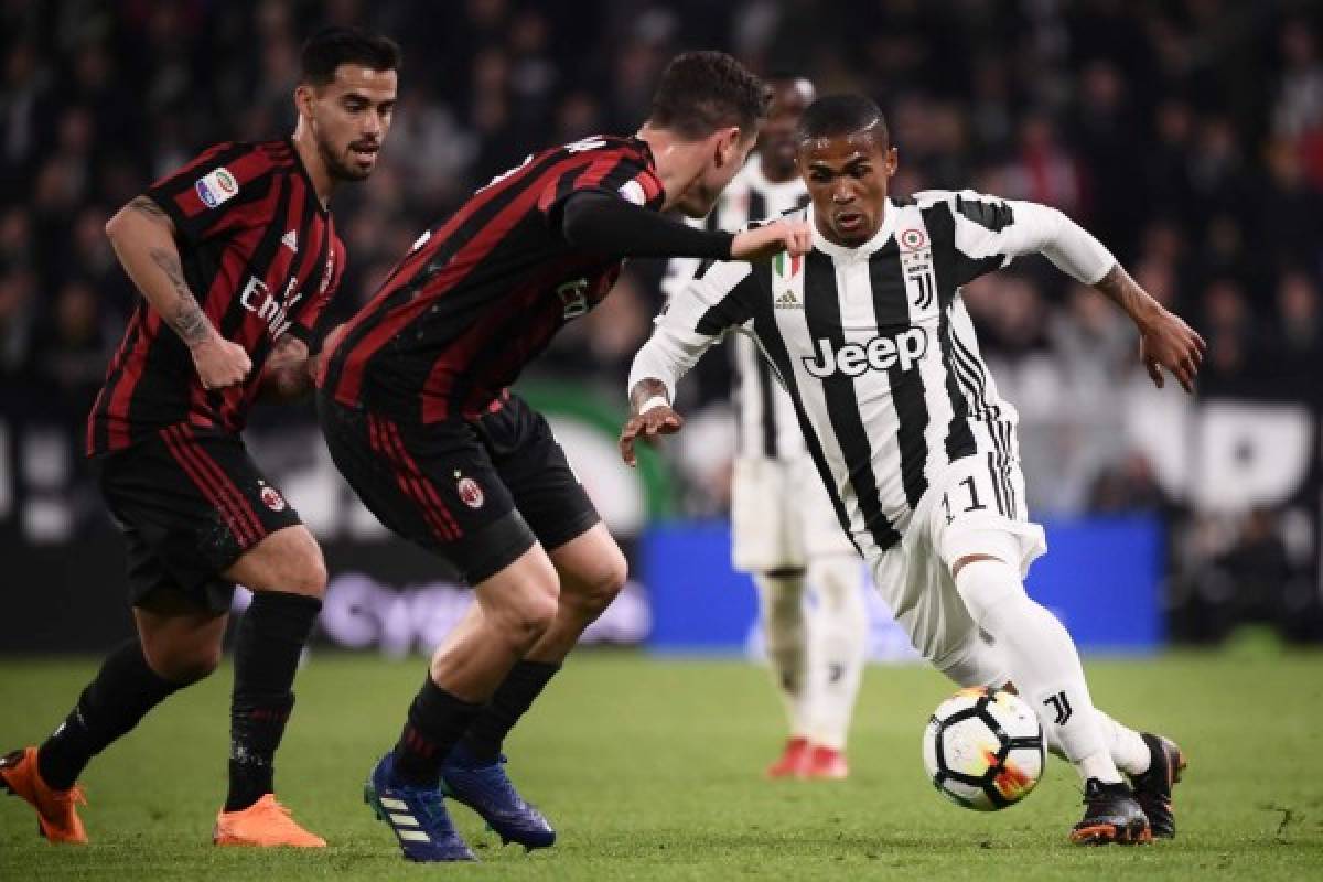 AC Milan's midfielder Suso from Spain (L) fights for the ball with Juventus' midfielder Douglas Costa from Brazil during the Italian Serie A football match Juventus Vs AC Milan on March 31, 2018 at the 'Allianz Stadium' in Turin. / AFP PHOTO / MARCO BERTORELLO