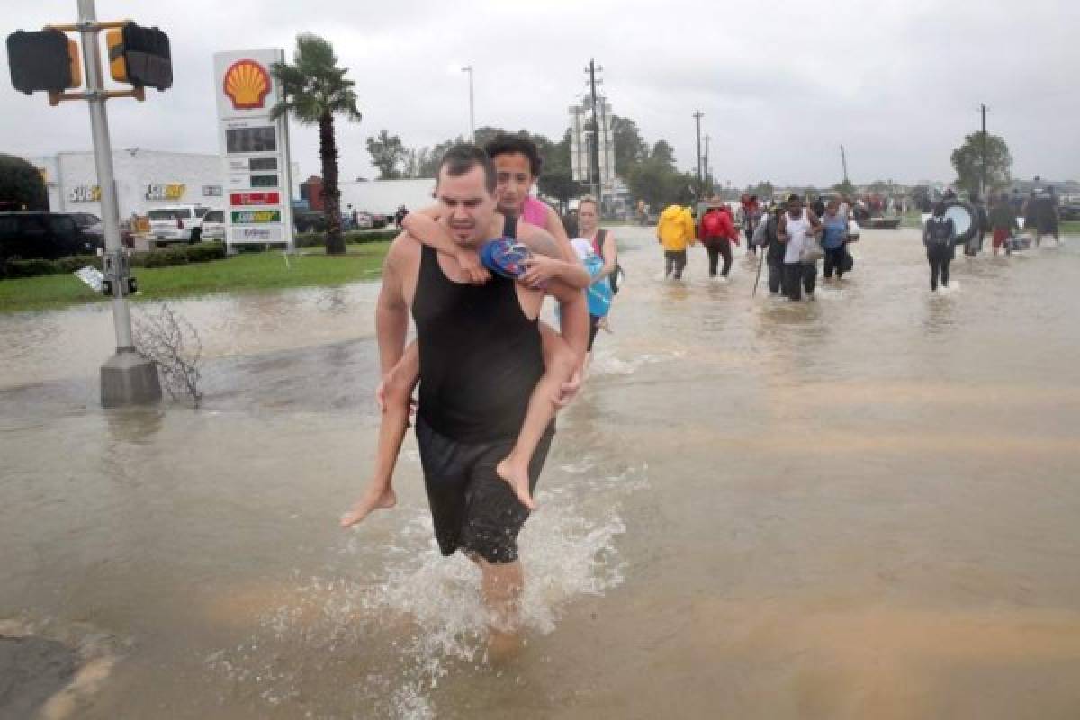 HOUSTON, TX - AUGUST 28: People make their way out of a flooded neighborhood after it was inundated with rain water, remnants of Hurricane Harvey, on August 28, 2017 in Houston, Texas. Harvey, which made landfall north of Corpus Christi late Friday evening, is expected to dump upwards to 40 inches of rain in areas of Texas over the next couple of days. Scott Olson/Getty Images/AFP