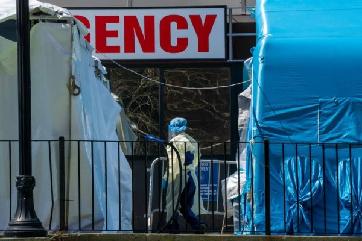 NEW YORK, NY - APRIL 15: A medical worker walks in between Covid-19 testing tents at the Elmhurst Medical Center on April 15, 2020, in Queens borough of New York City. During his daily briefing New York Gov. Andrew Cuomo said he would invoke an executive order requiring citizens to wear facial coverings while in public and in situations when social distancing is not possible. David Dee Delgado/Getty Images/AFP