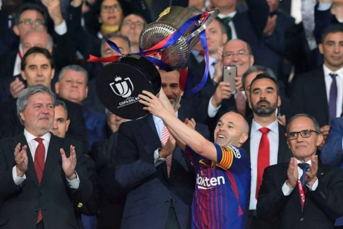 Barcelona's Spanish midfielder Andres Iniesta (C) holds the trophy next to Spain's king Felipe VI after the Spanish Copa del Rey (King's Cup) final football match Sevilla FC against FC Barcelona at the Wanda Metropolitano stadium in Madrid on April 21, 2018. Barcelona won 5-0. / AFP PHOTO / LLUIS GENE