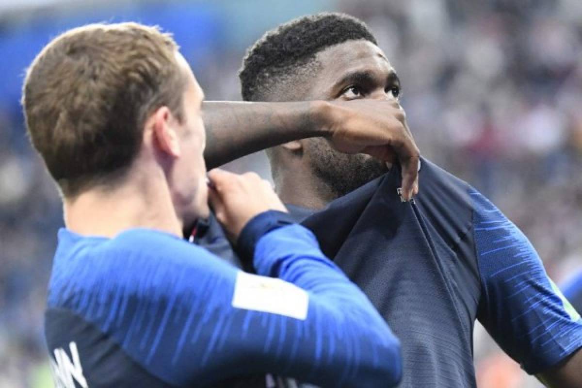 France's defender Samuel Umtiti (R) kisses his jersey as he celebrates scoring the opening goal with France's forward Antoine Griezmann during the Russia 2018 World Cup semi-final football match between France and Belgium at the Saint Petersburg Stadium in Saint Petersburg on July 10, 2018. / AFP PHOTO / CHRISTOPHE SIMON / RESTRICTED TO EDITORIAL USE - NO MOBILE PUSH ALERTS/DOWNLOADS