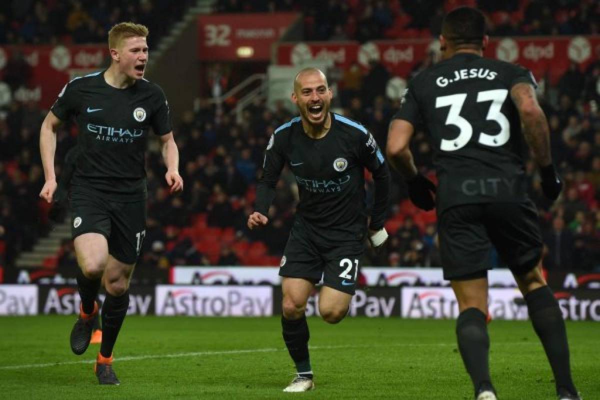 Manchester City's Spanish midfielder David Silva (C) celebrates with Manchester City's Belgian midfielder Kevin De Bruyne (L) and Manchester City's Brazilian striker Gabriel Jesus as he celebrates scoring his second goal of the English Premier League football match between Stoke City and Manchester City at the Bet365 Stadium in Stoke-on-Trent, central England on March 12, 2018. / AFP PHOTO / PAUL ELLIS / RESTRICTED TO EDITORIAL USE. No use with unauthorized audio, video, data, fixture lists, club/league logos or 'live' services. Online in-match use limited to 75 images, no video emulation. No use in betting, games or single club/league/player publications. /