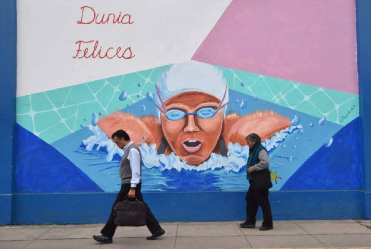 Locals walk past murals on the walls of a municipal stadium in Lima on July 17, 2019, depicting national sportsmen and women participating in the Lima-2019 Pan-American Games that will take place from July 26 to August 11. - Over 600 Peruvian athletes are expected to participate in the Lima 2019 Pan American Games. (Photo by Cristobal BOURONCLE and CRIS BOURONCLE / AFP)