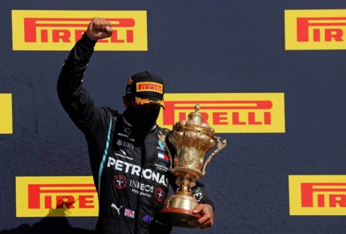 Winner Mercedes' British driver Lewis Hamilton celebrates with his trophy on the podium after the Formula One British Grand Prix at the Silverstone motor racing circuit in Silverstone, central England on August 2, 2020. - Lewis Hamilton survived a dramatic finale to win the British Grand Prix on Sunday, just making it across the line on three tyres to beat a fast closing Max Verstappen on Red Bull. The defending world champion claimed his seventh British Grand Prix win as Ferarri's Charles Leclerc came third and Daniel Ricciardo of Renault fourth. (Photo by Frank Augstein / POOL / AFP)
