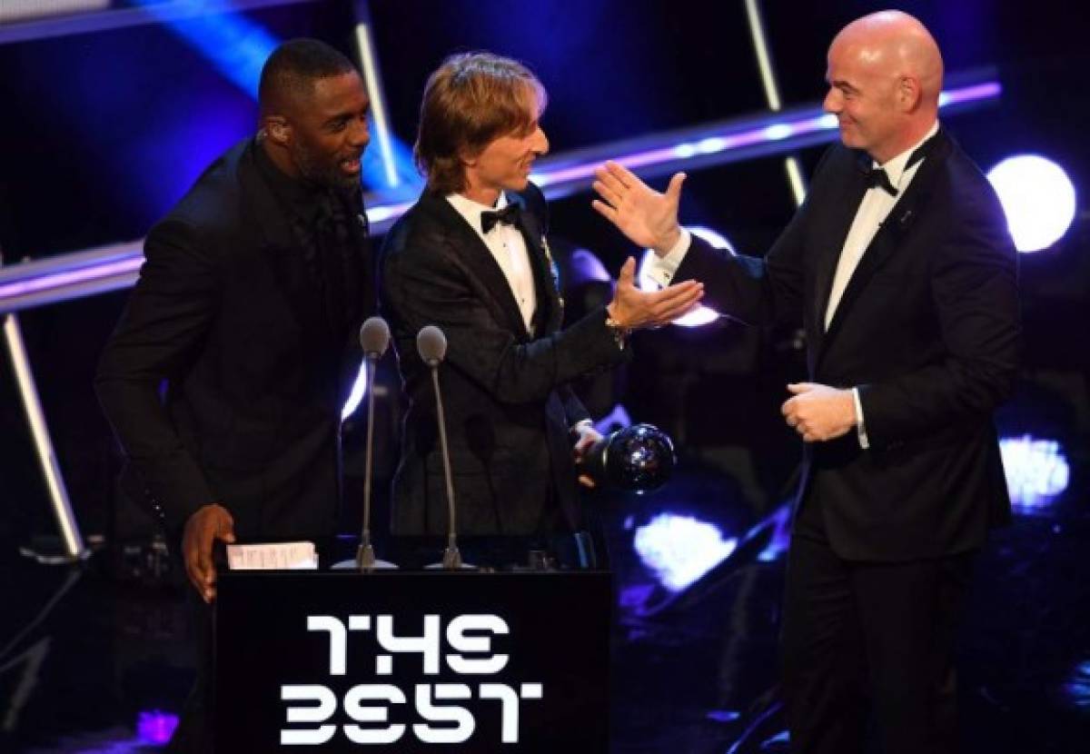 British actor and event host Idris Elba (L) speaks as Real Madrid and Croatia midfielder Luka Modric (C) and FIFA president Gianni Infantino (R) shake hands after Modric wins the trophy for the Best FIFA Men's Player of 2018 Award during The Best FIFA Football Awards ceremony, on September 24, 2018 in London. / AFP PHOTO / Ben STANSALL