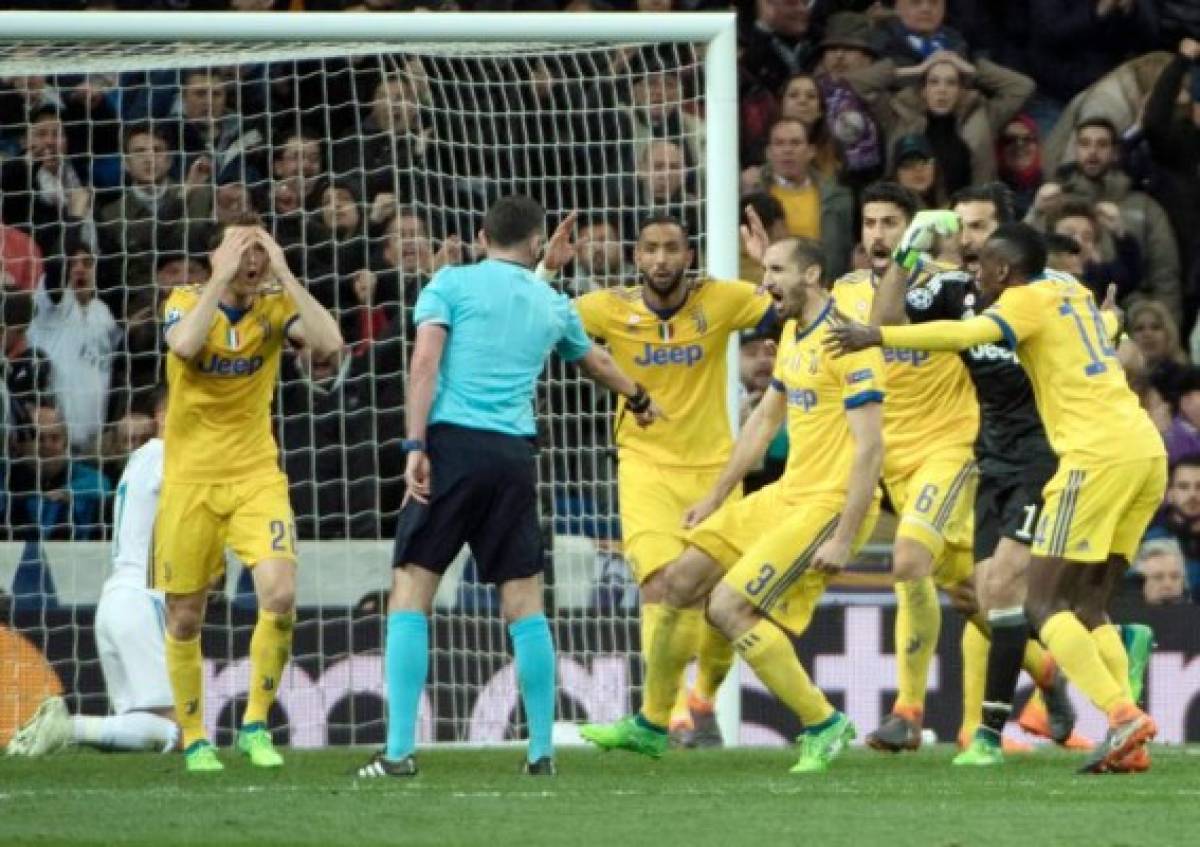 Juventus players protest as English referee Michael Oliver (2L) signals a penalty kick during the UEFA Champions League quarter-final second leg football match between Real Madrid CF and Juventus FC at the Santiago Bernabeu stadium in Madrid on April 11, 2018. / AFP PHOTO / CURTO DE LA TORRE
