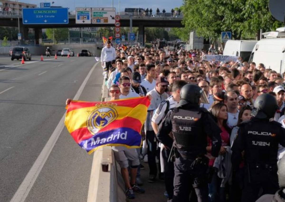 Police officers stand beside Real Madrid supporters waiting for entering the stadium before the UEFA Champions League semifinal second leg football match Club Atletico de Madrid vs Real Madrid CF at the Vicente Calderon stadium in Madrid, on May 10, 2017. / AFP PHOTO / CESAR MANSO