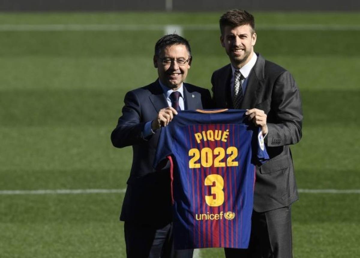 Barcelona's Spanish defender Gerard Pique (R) holds his jersey with Barcelona FC president Josep Maria Bartomeu as they pose during the official announcement of his contract renewal at the Camp Nou stadium in Barcelona on January 29, 2018. / AFP PHOTO / LLUIS GENE