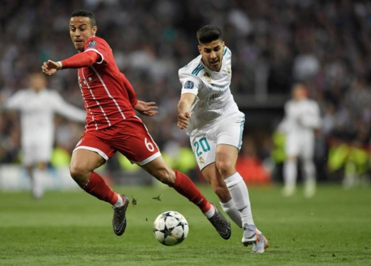 Bayern Munich's Spanish midfielder Thiago Alcantara (L) and Real Madrid's Spanish midfielder Marco Asensio vie for the ball during the UEFA Champions League semi-final second-leg football match Real Madrid CF vs FC Bayern Munich in Madrid, Spain, on May 1, 2018. / AFP PHOTO / GABRIEL BOUYS