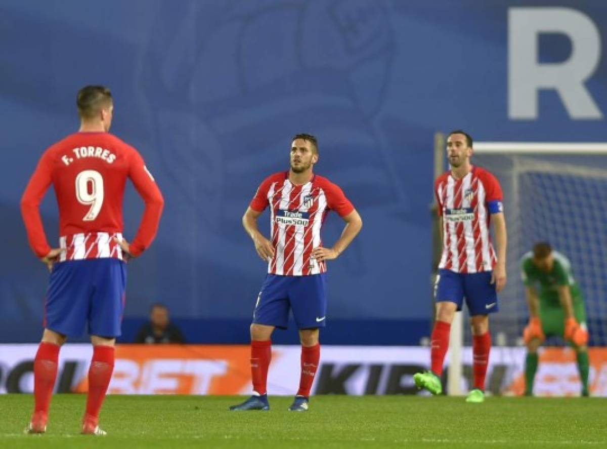 Atletico Madrid's Spanish forward Fernando Torres (L), Atletico Madrid's Spanish midfielder Koke (C) and Atletico Madrid's Uruguayan defender Diego Godin stand on the field after Real Sociedad's third goal during the Spanish league football match Real Sociedad vs Club Atletico de Madrid at the Anoeta stadium in San Sebastian on April 19, 2018. / AFP PHOTO / ANDER GILLENEA