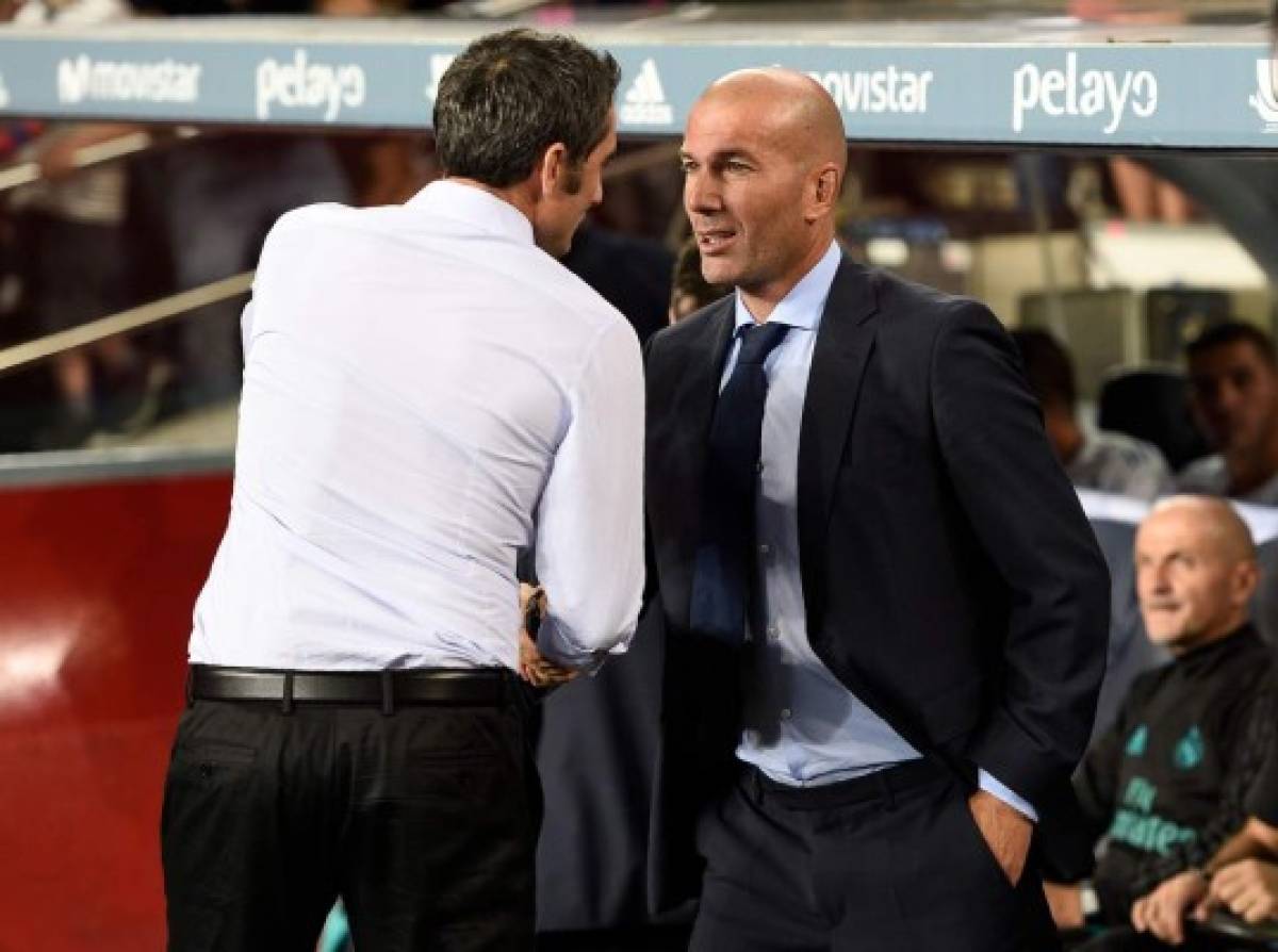 Barcelona's coach Ernesto Valverde (L) talks with Real Madrid's French coach Zinedine Zidane (R) before the Spanish Supercup first leg football match FC Barcelona vs Real Madrid at the Camp Nou stadium in Barcelona on August 13, 2017. / AFP PHOTO / LLUIS GENE