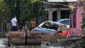 A man looks on near a destroyed car and sofas covered in mud after the passage of Hurricane Eta, now downgraded to Tropical Storm, in Planeta, municipality of La Lima, in the Honduran department of Cortes, on November 9, 2020. - Tropical Storm Eta made landfall at the Florida Keys late Sunday, bringing heavy rains and strong winds after slamming Cuba and earlier cutting a deadly path through Central America and southern Mexico. At least 200 people are dead or missing after Eta -- initially classified as a hurricane -- ripped through Nicaragua, Guatemala, and Honduras, causing flooding and landslides. (Photo by Orlando SIERRA / AFP)