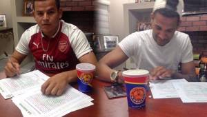 Kevin Espinoza, con la camiseta del Arsenal de Inglaterra, firmando su contrato con Marathón; Yaudel Lahera también renovó.