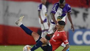 El hondureño Carlos Fernández del Fénix de Uruguay disputa la pelota con el chileno Pedro Hernández del Independiente quien se cae en la acción. Foto AFP