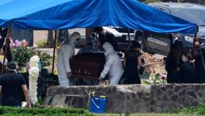 Funeral home employees wear protective suits against the spread of the new coronavirus as they carry the coffin of Honduran former president (1990-1994) Rafael Leonardo Callejas during his funeral in Tegucigalpa on April 11, 2020. - Callejas, who was linked to the FIFA Gate corruption case, died from leukemia in Atlanta, Giorgia, USA on April 4. (Photo by ORLANDO SIERRA / AFP)