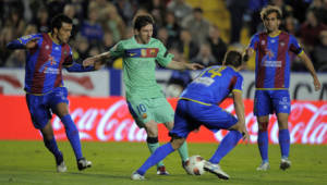 Jugadores del Levante intentar arrebatarle el balón a Lio Messi durante el choque.