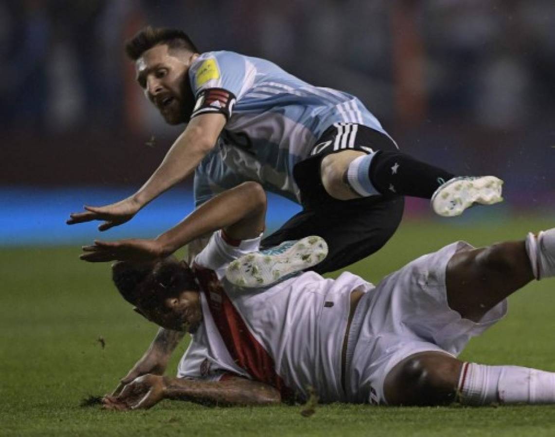 Argentina's Lionel Messi and Peru's Wilder Cartagena fall during their 2018 World Cup football qualifier match in Buenos Aires on October 5, 2017. / AFP PHOTO / JUAN MABROMATA