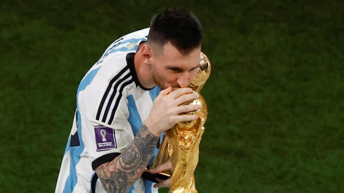 Messi besando la Copa del Mundo y sosteniendo el Balón de Oro del Mundial.