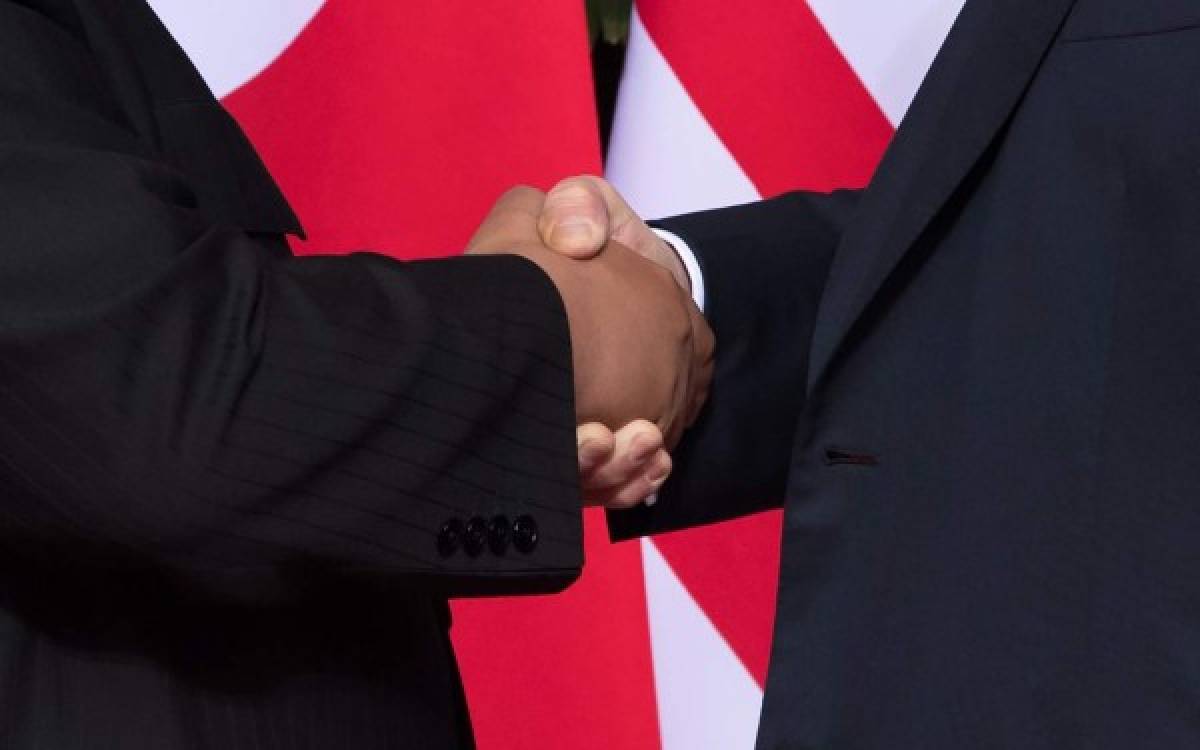 US President Donald Trump (R) shakes hands with North Korea's leader Kim Jong Un (L) at the start of their historic US-North Korea summit, at the Capella Hotel on Sentosa island in Singapore on June 12, 2018.Donald Trump and Kim Jong Un became on June 12 the first sitting US and North Korean leaders to meet, shake hands and negotiate to end a decades-old nuclear stand-off. / AFP PHOTO / SAUL LOEB