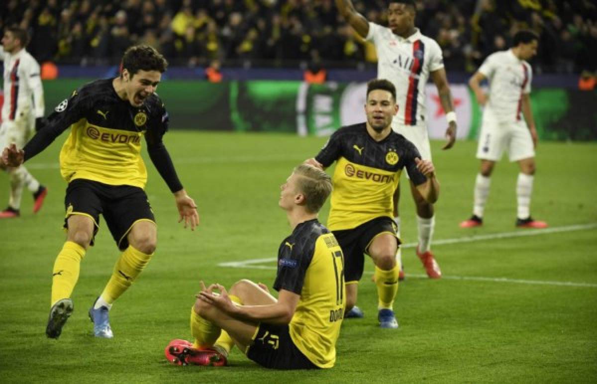 Dortmund's Norwegian forward Erling Braut Haaland (C) is congratulated by his teammates Dortmund's US midfielder Giovanni Reyna (L) and Dortmund's Portuguese defender Raphael Guerreiro (R) after scoring the 1-0 during the UEFA Champions League Last 16, first-leg football match BVB Borussia Dortmund v Paris Saint-Germain (PSG) in Dortmund, western Germany, on February 18, 2020. (Photo by Ina Fassbender / AFP)