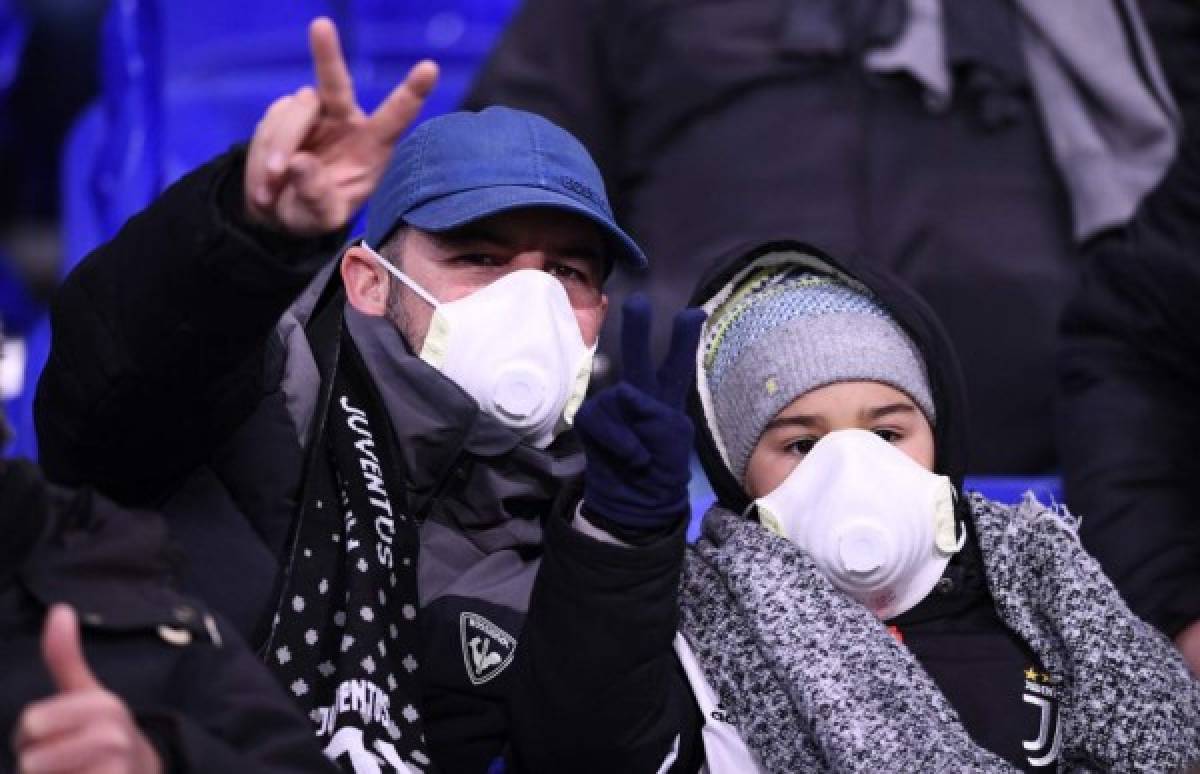 Juventus supporters wear protective face masks as a safety measure against the COVID-19 novel coronavirus at the Parc Olympique Lyonnais stadium in Decines-Charpieu, central-eastern France, on February 26, 2020, ahead of the UEFA Champions League round of 16 first-leg football match between Lyon and Juventus. (Photo by FRANCK FIFE / AFP)