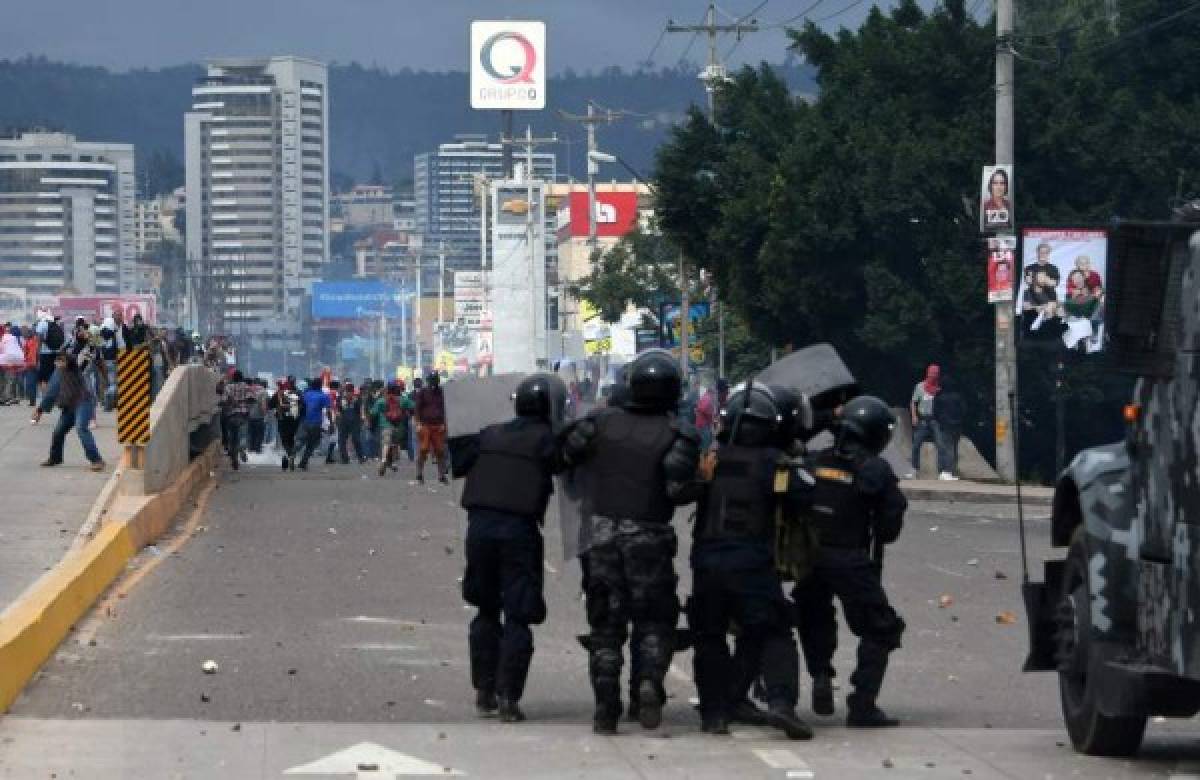 Angry supporters of Honduran presidential candidate for the Opposition Alliance against the Dictatorship coalition, Salvador Nasralla, clash with the police near the Electoral Supreme Court (TSE), as the country waits for the final results of the week-end's presidential election, in Tegucigalpa, on November 30, 2017. Honduran President Juan Orlando Hernandez edged closer Thursday to winning a tense election as rival Nasralla said he will not recognize the result, claiming fraud. In a vote count dogged by computer failures and claims by Nasralla that the president was stealing the election, Hernandez had overturned a 5.0 percent deficit by early Thursday to lead by just 1.0 percent with 90 percent of the votes counted. / AFP PHOTO / Orlando SIERRA