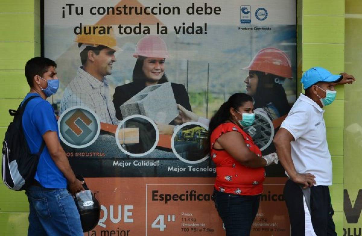 People queueing at a ironmonger's wear face masks as a preventive measure against the spread of the novel coronavirus COVID-19, in Tegucigalpa on April 20, 2020. - More than 160,000 people have died from the new coronavirus around the world according to an AFP tally at 0940 GMT Sunday based on official sources. (Photo by Orlando SIERRA / AFP)